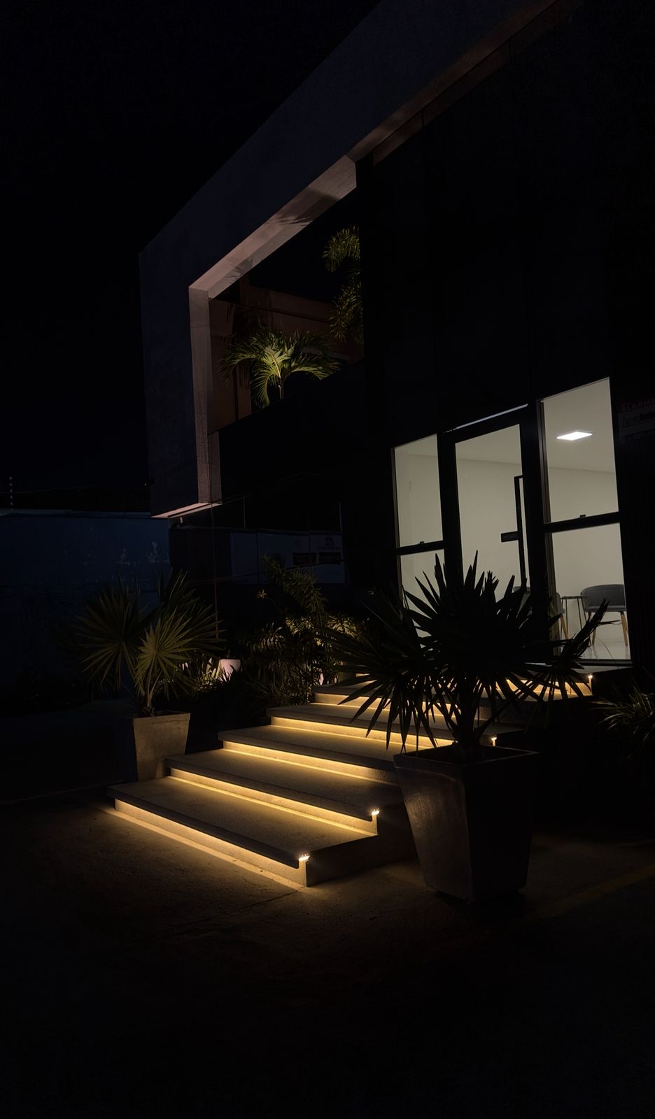 Fachada externa da clínica com iluminação noturna e paisagismo